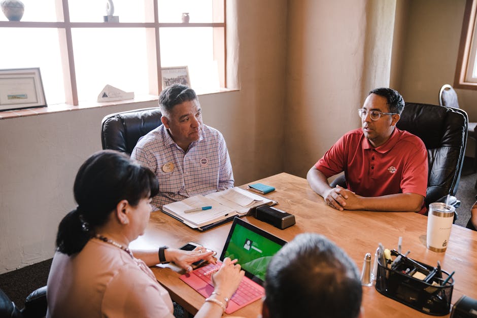 Colleagues discuss ideas in an office setting, emphasizing teamwork.