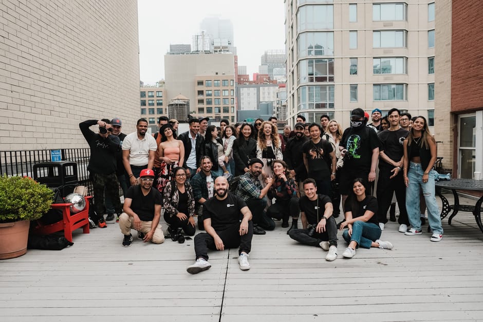A diverse group of friends posing for a photo on a rooftop with cityscape background.